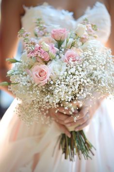 a bride holding a bouquet of white and pink flowers