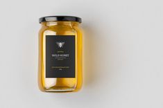 a glass jar filled with honey sitting on top of a white table next to a wall