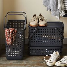 two pairs of shoes are sitting on the floor next to baskets with clothes in them