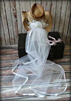 a cowboy hat and veil on top of a wooden box next to a piece of luggage