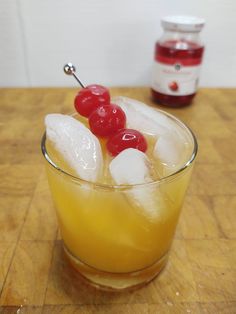 two cherries on top of ice in a glass filled with lemonade and orange juice