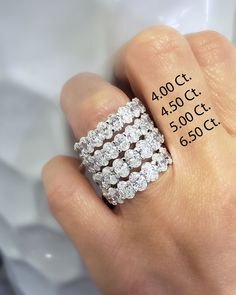 a woman's hand holding a diamond ring with the price label below it and in front of her