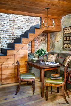 a living room filled with furniture next to a stair case and wooden floored walls