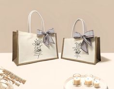 two bags with bows on them sitting next to candles