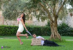 a man holding a sign next to a woman laying on the ground in front of a tree