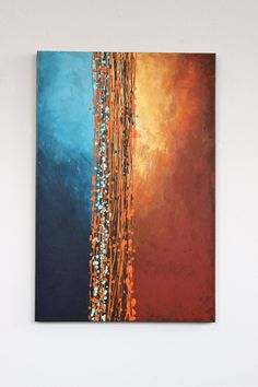 a painting hanging on the wall above a vase with an orange and blue flower arrangement