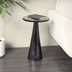 a black table with a book on it next to a couch and potted plant