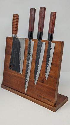 four knives are in a wooden holder on a white background