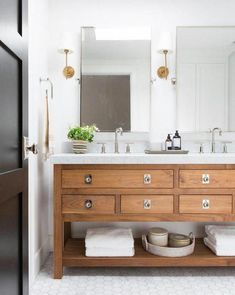 a bathroom vanity with two sinks and wooden drawers in front of a mirror above it