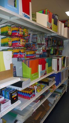 the shelves are filled with many different colored books and binder folders on them