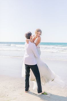 a bride and groom hug on the beach