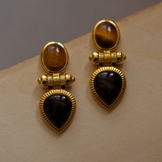 Earrings made of glittering tiger's eye stone and black agate bordered in gold and connected by a rotating shaft. An item that will make you look like a glamorous and elegant lady. Earrings with a strong presence add color to a beautiful lady. It has a retro atmosphere that is timeless. 
 
 
 Item 
 
 Earrings 
 Earrings 
 
 
 Size 
 
 Height: 2.9cm 
 Width: 1.2cm 
 
 
 Material 
 
 Alloy 
 Tiger's eye stone 
 Black agate 
 
 
 Others 
 
 If you have a metal allergy or the plating does not suit Lines And Shapes, Black Onyx Earrings, Cats Eye Stone, Agate Earrings, Onyx Earrings, Design Earrings, Tiger Eye Stone, Black Agate, Eye Stone