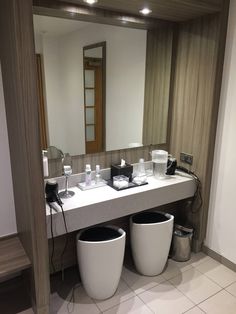 a bathroom counter with two trash cans on it and a mirror in the back ground