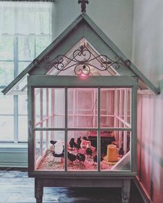 a doll house with animals inside and in the front window is lit by a pink light