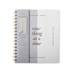 a spiral notebook with the words, one thing at a time written in black and white