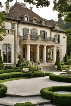 a large white house with lots of windows and bushes in front of it, surrounded by greenery