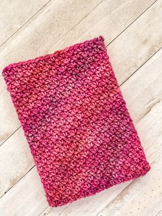 a pink and red knitted cloth on a white wooden floor