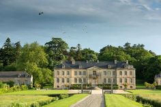 a large house in the middle of a lush green field