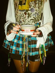 a woman wearing a skirt and holding a bowl