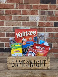 a game night box filled with candy and snacks on top of a wooden table next to a brick wall