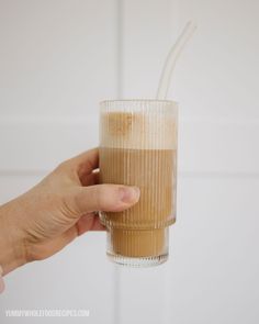 a person holding a glass with some liquid in it and straws sticking out of the top