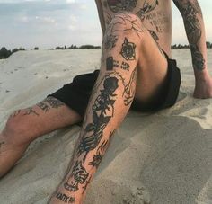 a man with tattoos sitting in the sand