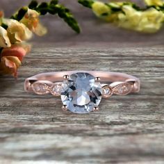 an oval cut blue topazte and diamond ring on a wooden table with flowers in the background