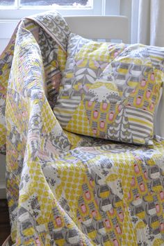 a yellow and gray quilt on a chair in front of a window