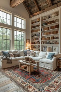 a living room filled with furniture and bookshelves next to a large window on top of a wooden floor