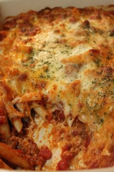 a casserole dish with meat and cheese on top, in a white bowl