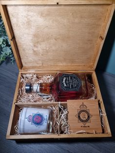 an open wooden box containing two bottles of liquor and a shot glass in the case