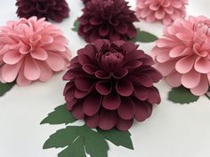 paper flowers arranged on top of each other in pink and purple colors with green leaves