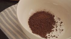 a white bowl filled with brown powder and cocoa