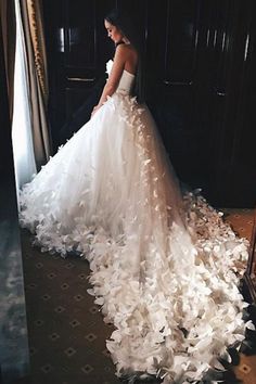 a woman in a wedding dress is standing near a mirror with petals all over it