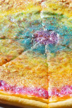 a colorful pizza sitting on top of a pan covered in sauce and sprinkles