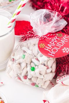 a glass of milk and some candy on a white table with red tinsels