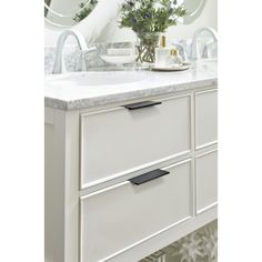 a white bathroom vanity with two sinks and large mirrors on the wall above it,