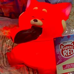 a red plastic toy bear sitting next to a package of chewing gums and other toys