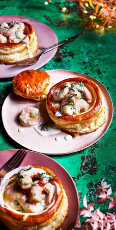 three pink plates topped with food on top of a green table