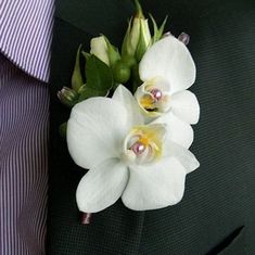 a man wearing a suit and tie with white flowers on his lapel flower pin