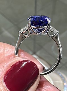 a close up of a person holding a ring with a blue stone on the side