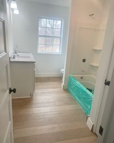 an empty bathroom with wood floors and white walls