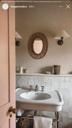 a white sink sitting under a bathroom mirror next to a wall mounted faucet