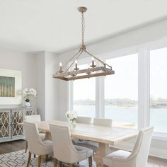 a dining room table with white chairs and a chandelier hanging from the ceiling