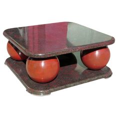 a red and black marble coffee table with two orange balls on each side, in front of a white background