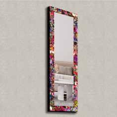 a mirror with flowers on it next to a wall