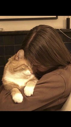 a woman is hugging her cat on the couch