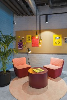 two chairs and a table in an office with posters on the wall behind them,