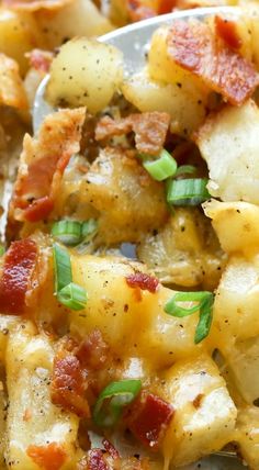 a close up of a spoon with some food on it and potatoes in the background