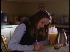 a woman sitting at a table writing on a piece of paper